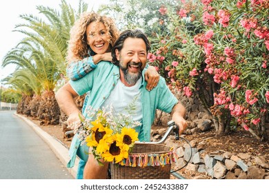 Happy couple spend happy time enjoying spring. Newlyweds together on a bike play and laugh. Concept of love and leisure - Powered by Shutterstock