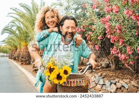 Happy couple spend happy time enjoying spring. Newlyweds together on a bike play and laugh. Concept of love and leisure