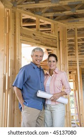 Happy Couple Stand Together Inside Their Home Under Construction. Vertical Shot.