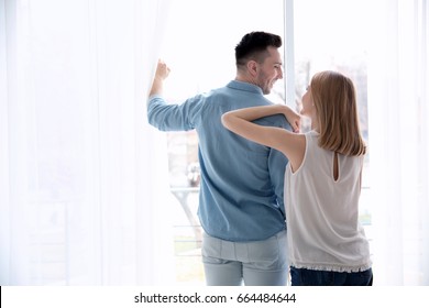 Happy Couple Standing Near Window And Opening Curtains