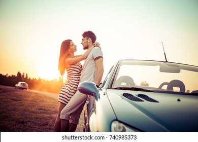 Happy couple standing next convertible car and looking at each other 