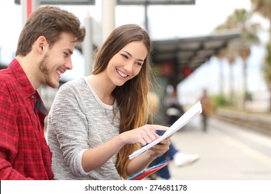 Happy couple of students studying and learning in a train station