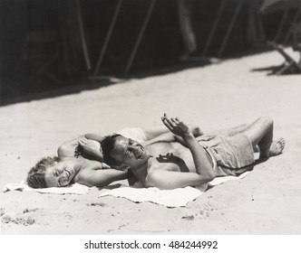 Happy Couple Sunbathing On Beach