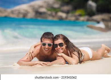 Happy Couple In Sunglasses Having Fun On The Beach. Summer Vacation. Laughing Family Enjoying Nature Over Sea Background. Attractive Man And Woman At The Beach. Sun Tan. Maldives. Seychelles.