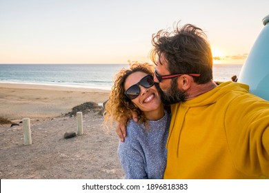 Happy couple take selfie picture at the beach with love and kiss - concept of people tourists enjoy the outdoor leisure activity in travel summer holiday vacation with sky and sunrise ocean view - Powered by Shutterstock