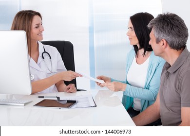 Happy Couple Taking Giving Card From Doctor