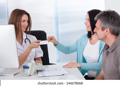 Happy Couple Taking Giving Card From Doctor