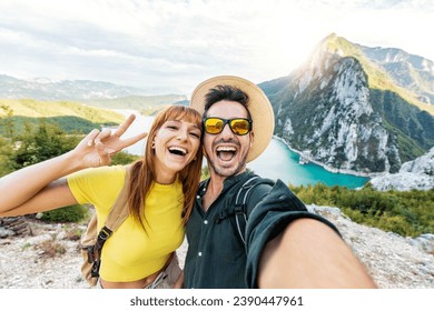 Happy couple taking selfie pic with smart mobile phone on top of the mountain - Young hikers climbing the cliff - Sport, technology and travel life style concept - Powered by Shutterstock