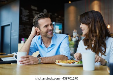 Happy couple talking at cafe, eating lunch