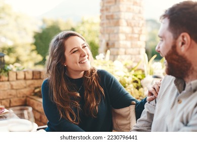 Happy couple, talking and outdoor on patio for a funny conversation while eating breakfast or lunch in summer. Woman and man together for happiness, love and care while laughing to relax on vacation