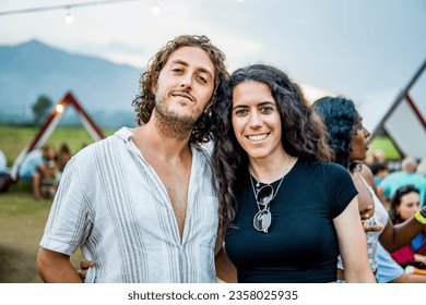 Happy Couple in Their 30s Posing at the Camera Smiling During a Party at a Hippie Festival Drinking in the Mountains - Powered by Shutterstock