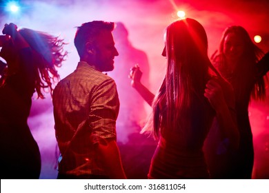Happy couple and their friends dancing in disco club