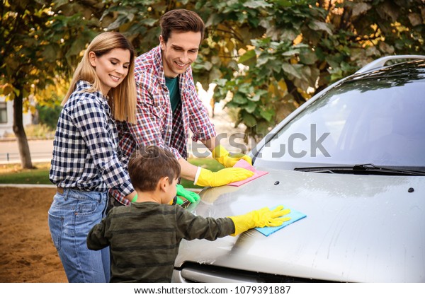 Happy\
couple with their little son washing car\
outdoors