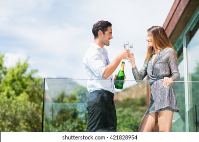 Happy Couple Toasting Champagne At Balcony In Resort