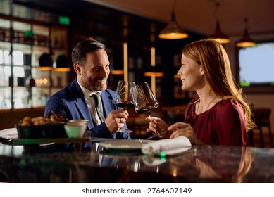 Happy couple toasting while drinking wine on a date night in restaurant. 