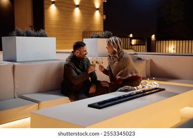 Happy couple toasting while relaxing by the fireplace on a patio in evening. Copy space.  - Powered by Shutterstock