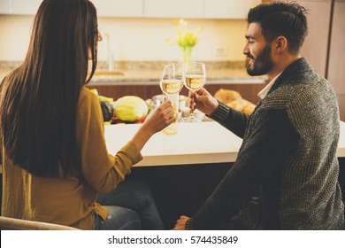 Happy couple toasting with white wine in the modern kitchen - Powered by Shutterstock