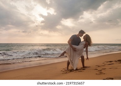 Happy Couple Together French Kissing On Tropical Sandy Beach At Sea Sunset Background. Beauty Couple Enjoying Honeymoon Summer At Ocean Coastline. Lovely Man And Woman Relaxing Happiness. Copy Space