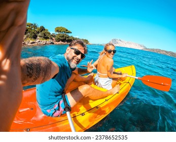 Feliz pareja de turistas tomándose selfie dentro de una canoa de kayak en vacaciones de verano, sonriendo y divirtiéndose con la cámara. Un hombre y una mujer alegres en un bote. Mar azul limpio y hermoso