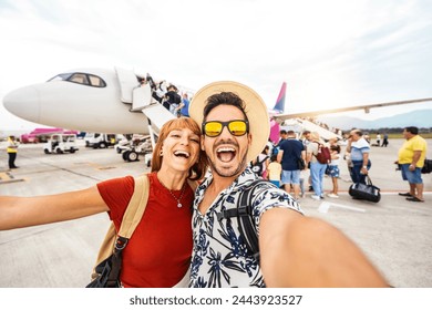 Happy couple of tourists boarding on a plane at the airport - Happy man and woman having happy summer vacation together - Transportation and holidays concept