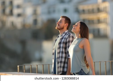 Happy couple in a town breathing fresh air from a rural apartment balcony - Powered by Shutterstock