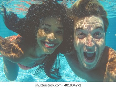 happy couple underwater. Smiling boy and girl making selfie in the swimming pool