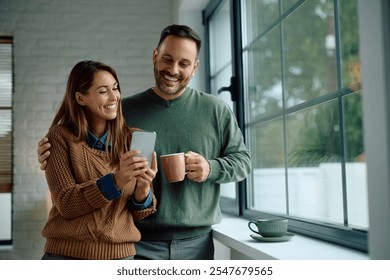 Happy couple using app on mobile phone by the window. Copy space.  - Powered by Shutterstock