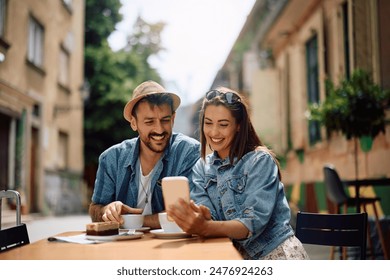 Happy couple using cell phone while drinking coffee in the city. - Powered by Shutterstock