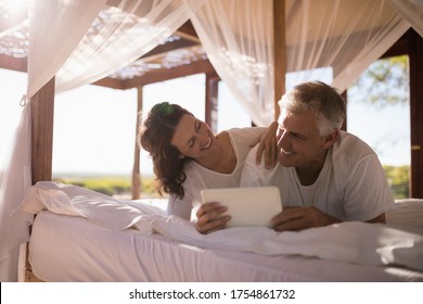 Happy couple using digital tablet on bed during morning