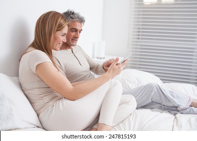 Happy Couple Using The Ipad In The Bed