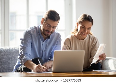 Happy Couple Using Laptop, Calculating Domestic Bills, Mortgage Or Loan Documents, Smiling Woman Holding Papers, Family Planning Budget, Managing Household Expenses, Focused Man Filling Form