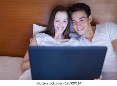 Happy couple using laptop at home.
