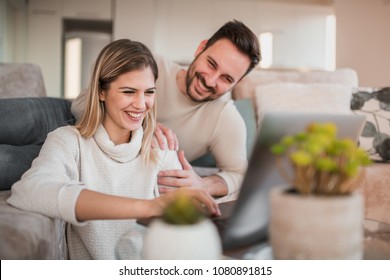 Happy Couple Using Laptop In Their Living Room.