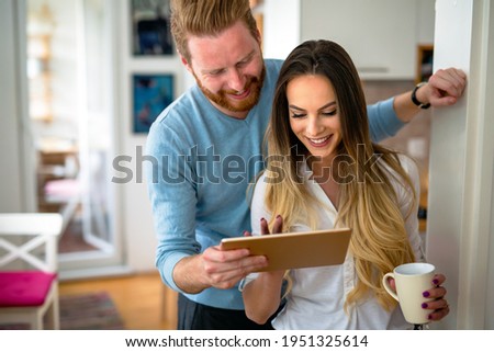 Happy couple using tablet and drinking coffee at home