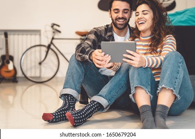 Happy couple using tablet at home - Young social people having fun with new trends technology devices - Tech and love relationship youth culture lifestyle concept 