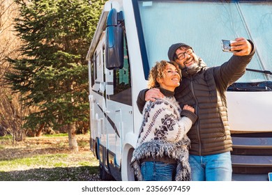 Happy couple of vanlife camper van tourist taking selfie picture with smartphone outside the travel vehicle home. Concept of tourism with rv camping car motorhome. Alternative lifestyle people smile - Powered by Shutterstock