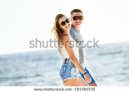 Happy couple is walking on the beach on background of sea
