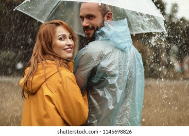 Happy couple walking under umbrella hiding from rain. They are turning in delight enjoying leisure together - Powered by Shutterstock