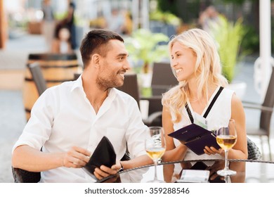 Happy Couple With Wallet Paying Bill At Restaurant