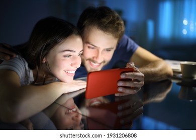 Happy Couple Watching Media Content On Horizontal Mobile Phone In The Night At Home