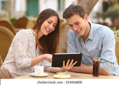 Happy couple watching media in a tablet in a restaurant terrace - Powered by Shutterstock