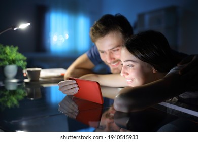 Happy Couple Watching Media Together On Smart Phone In The Night At Home