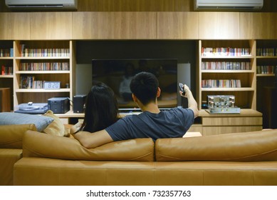 Happy Couple Watching A Movie In Living Room At Night