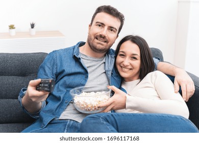 Happy couple watching television at home spending time