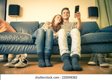 Happy Couple Watching Television On The Couch - Family,recreation,leisure,togetherness Concept