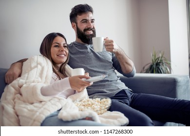 Happy Couple Watching Television,drink Coffee And Eat Popcorn On The Couch - Family,love,leisure And Lifestyle Concept.