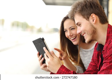 Happy couple watching videos or sharing media content from a tablet 