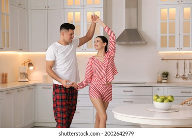 Happy Couple Wearing Pyjamas And Dancing In Kitchen