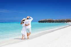 Una Pareja Feliz Vestida De Blanco Y Con Sombreros Camina Por Una Playa Tropical Con Mar Turquesa En Las Islas Maldivas