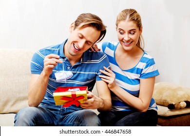 Happy couple - woman hugging her husband who holding gift box and baby shoe